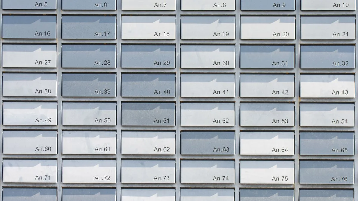 Rows of metallic apartment mailboxes organized in a neat, symmetrical grid pattern, creating a minimalist architectural design.