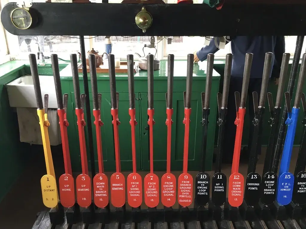 Rows of labelled red, black, yellow and blue levers in a railway signal box